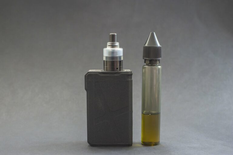 e-zigarette.jpg Ein Verdampfergerät links, daneben eine Flasche mit E-Liquid in einer transparenten Verpackung.